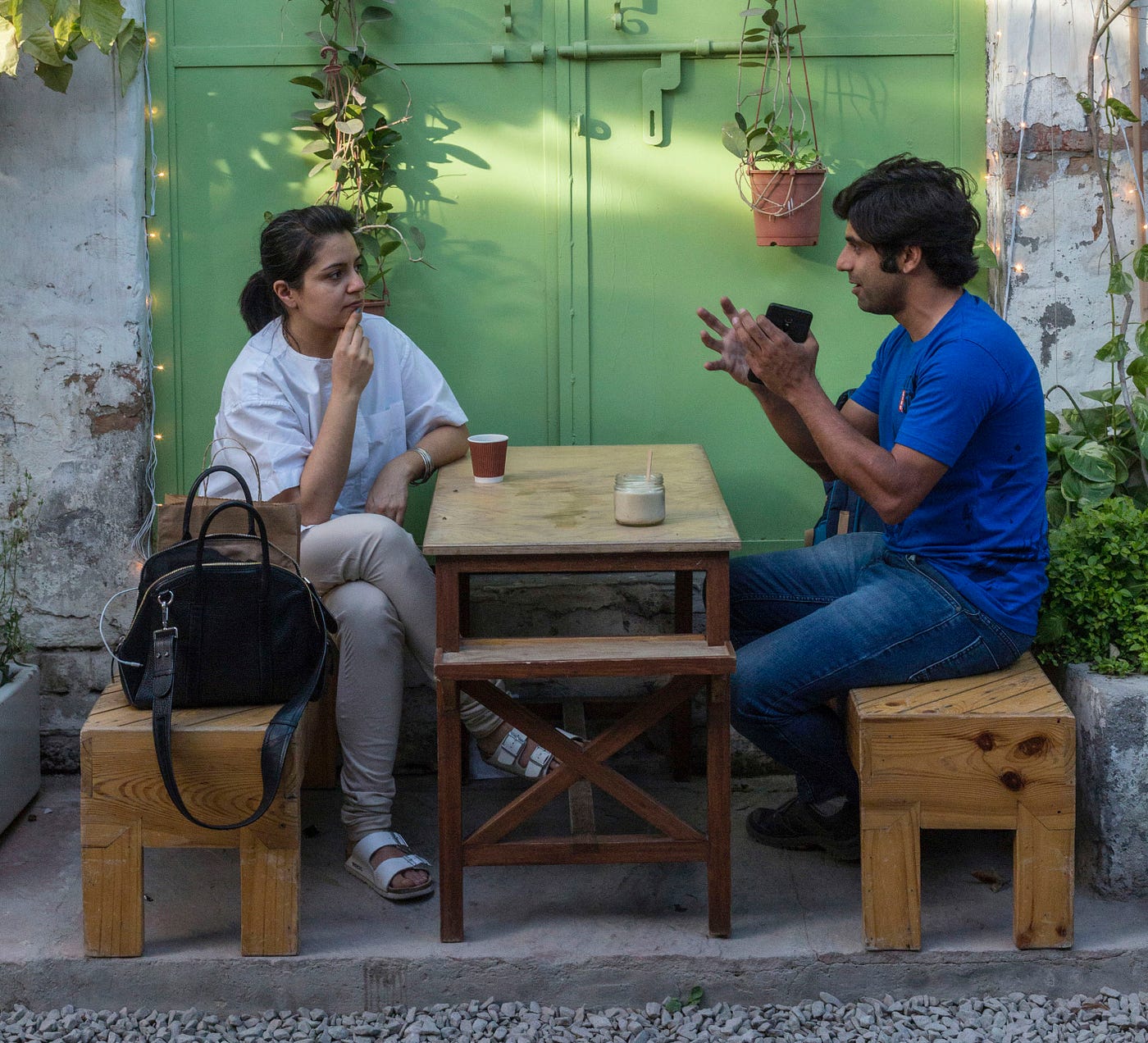 A man and a woman sitting at a coffee table. The woman is listening as the man is conversing over coffee.