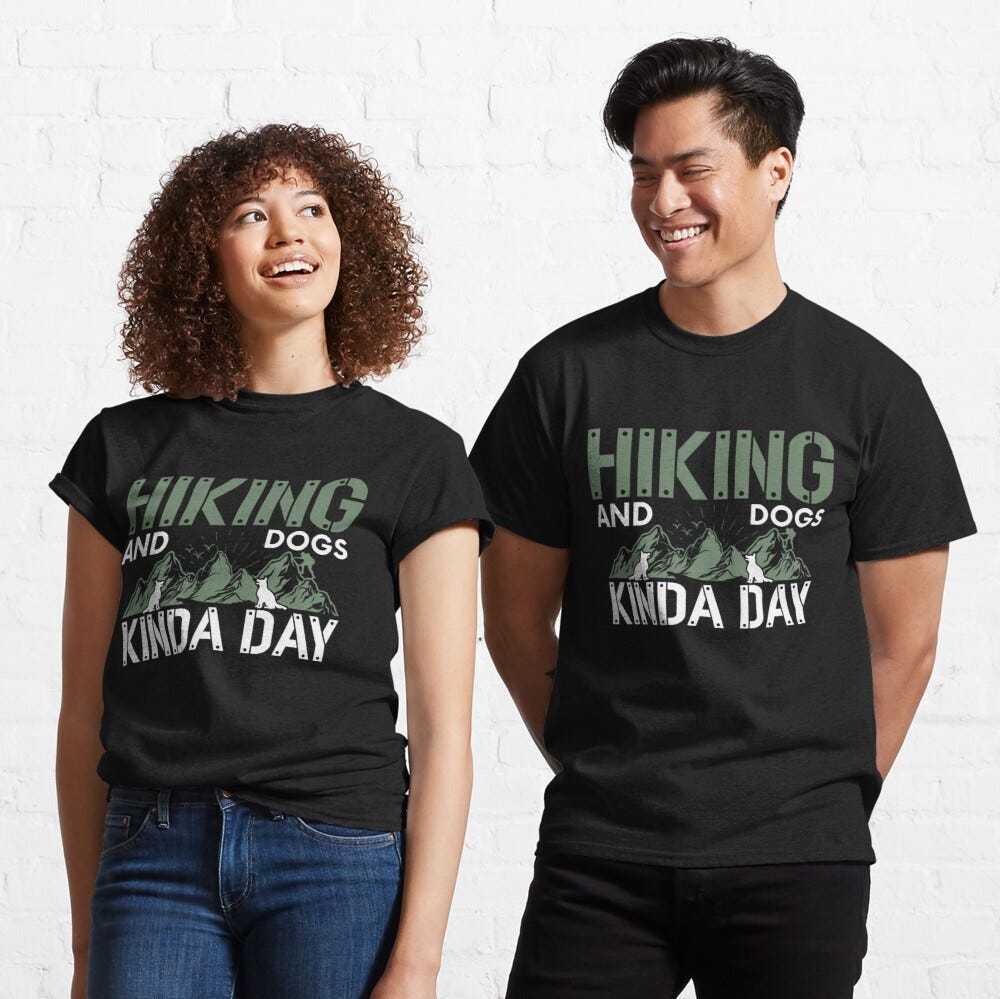 Man and Woman Wearing a black classic t-shirt with amazing illustration and text saying “hiking and dogs kinda day”.