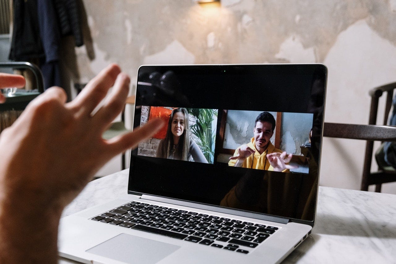 Laptop showing man and woman on screen with man communicating in sign language.