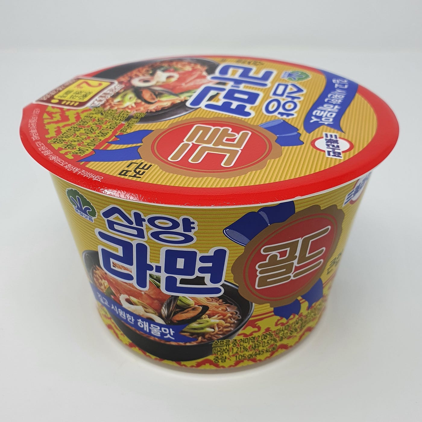 An unopened cup of Samyang Ramen Gold in a photo that features the top and front of the cup.