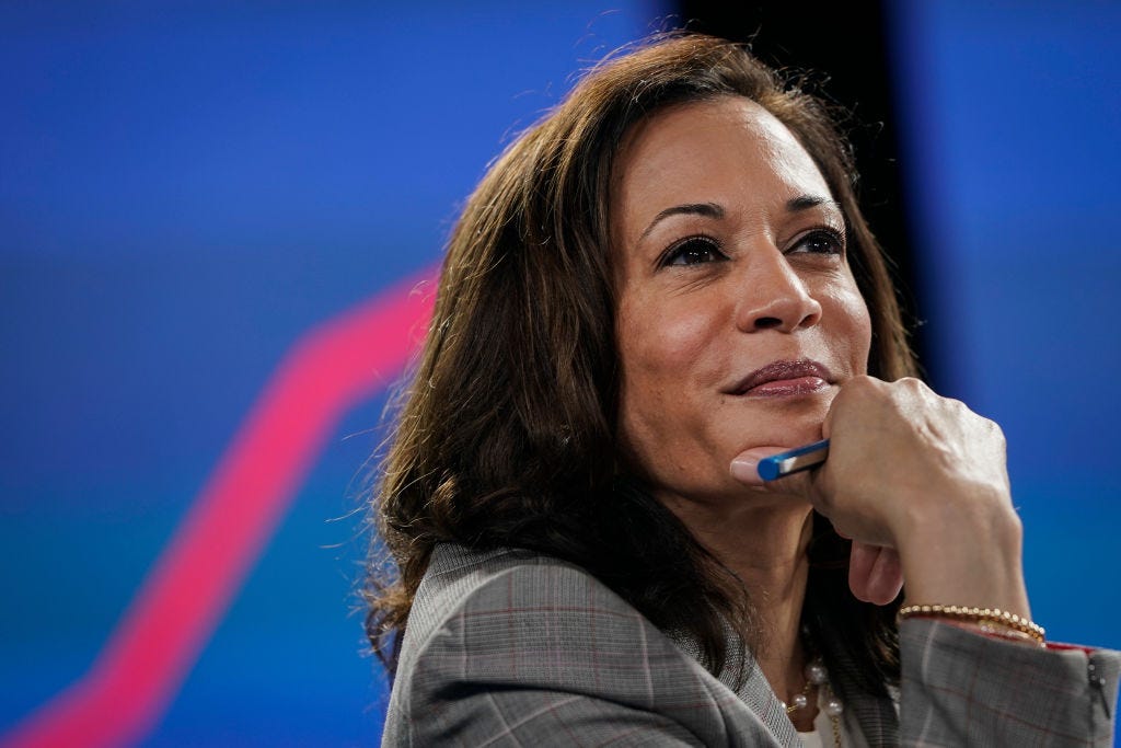 Closeup photo of Kamala Harris with a slight smile on her face, hand on chin.