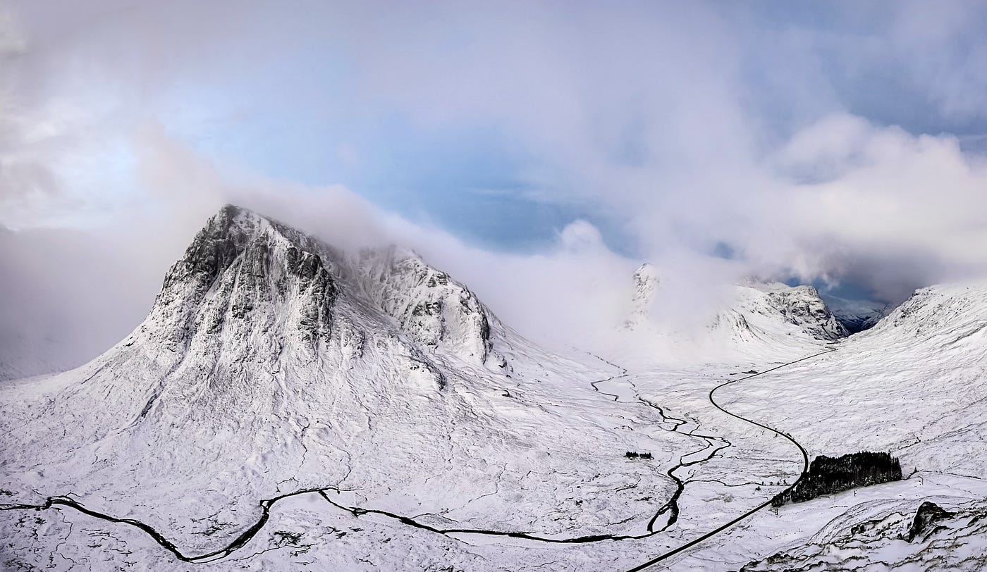 High mountain valley covered in snow with clouds brushing the mountaintops