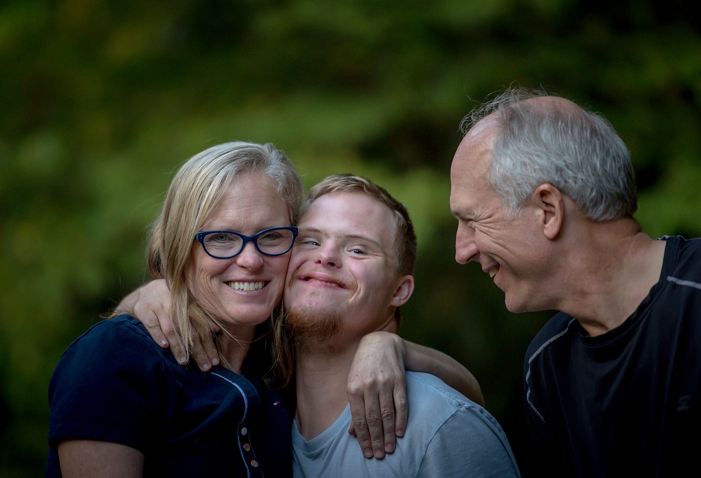 Family embracing a man with down syndrome and smiling to each other.