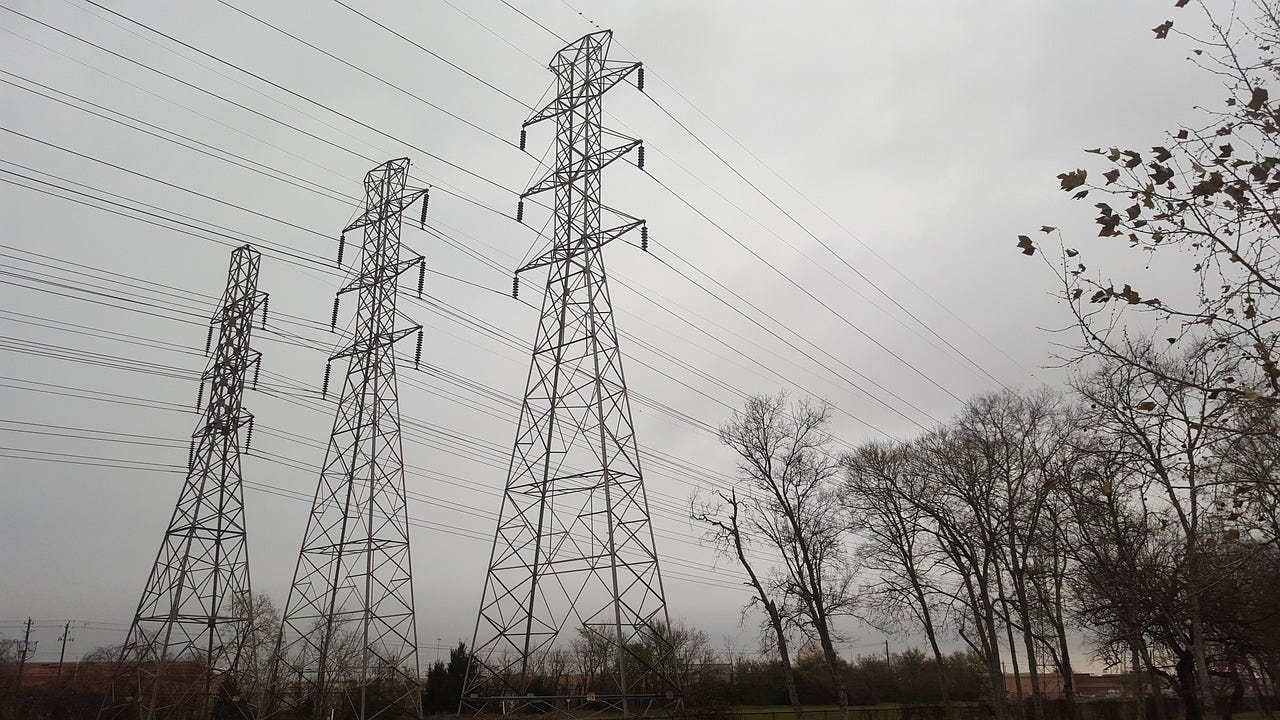 Power lines tower over a dark landscape