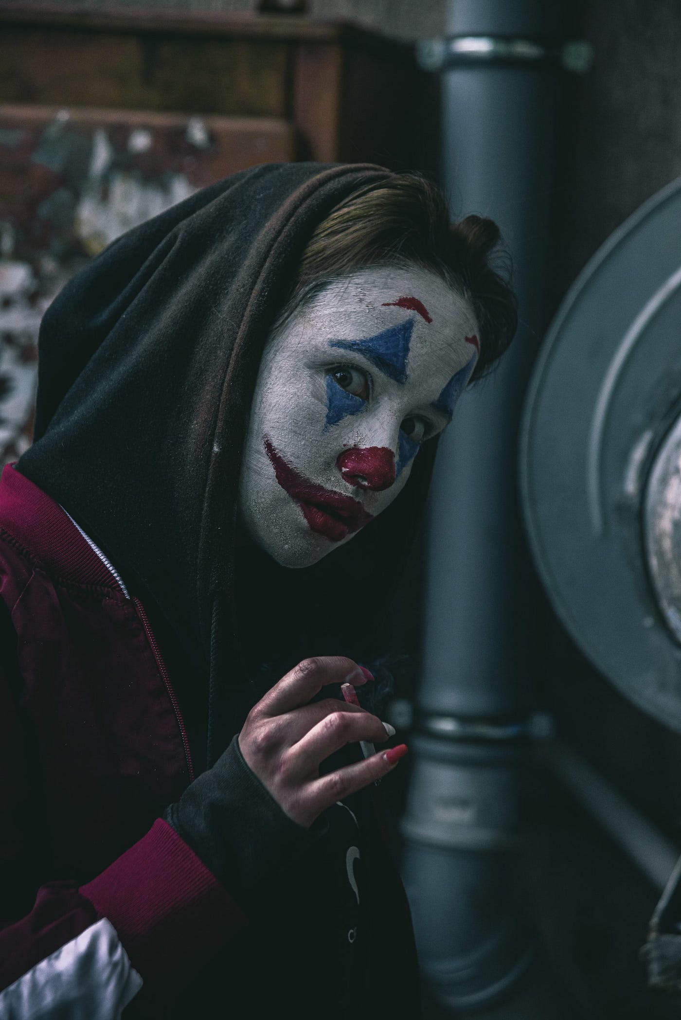 woman in clown face leaning on a pipe