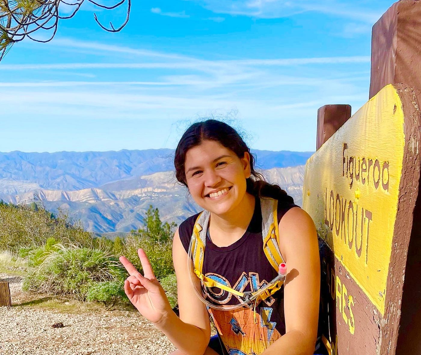 Liz throws up a peace sign next to a sign that says Figueroa Lookout