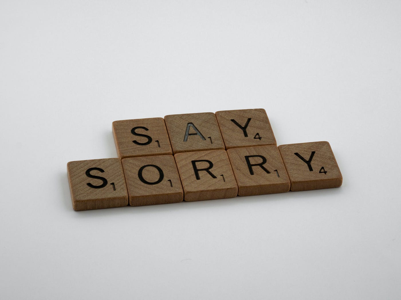 Scrabble tiles that spell out the words “Say Sorry”