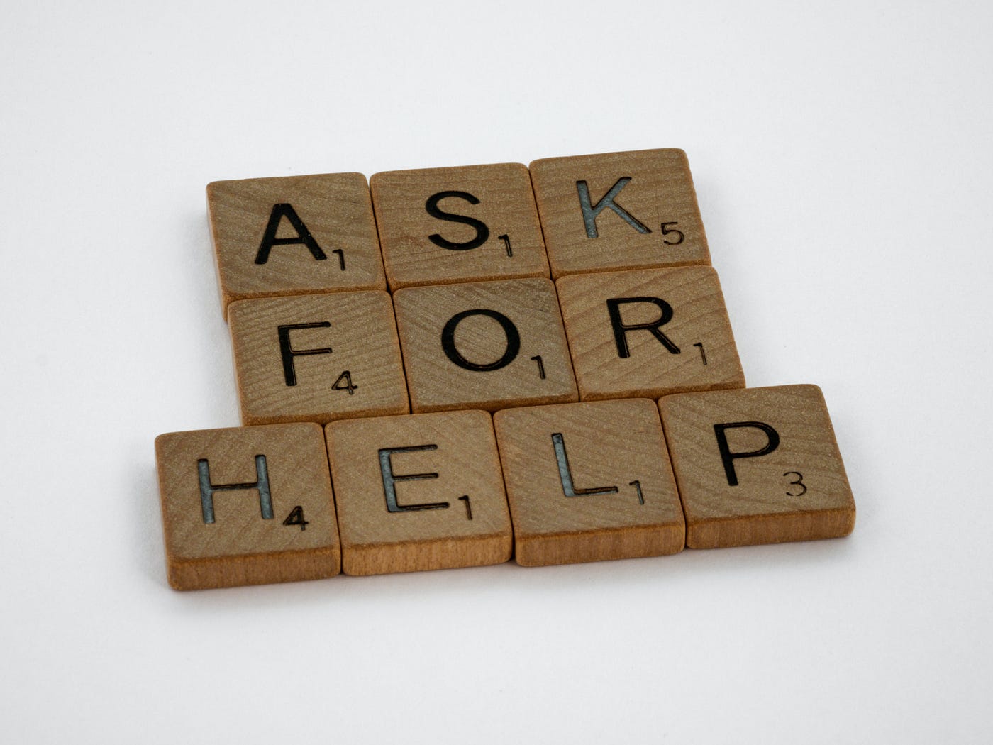 Ask for help spelled in scrabble tiles.