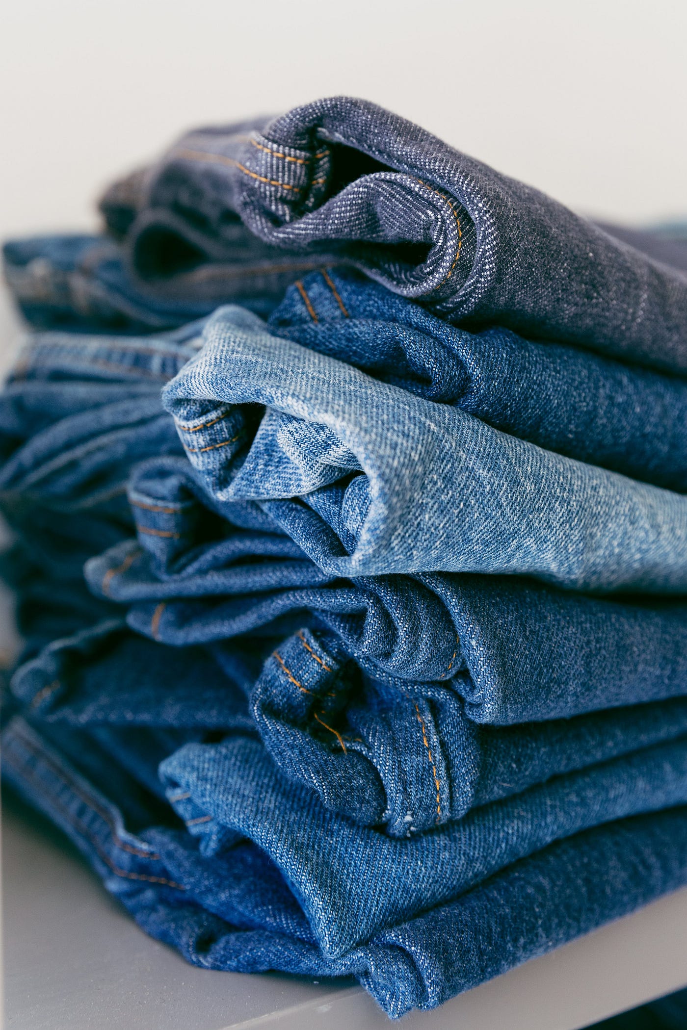 A pile of jeans in different shades of blue