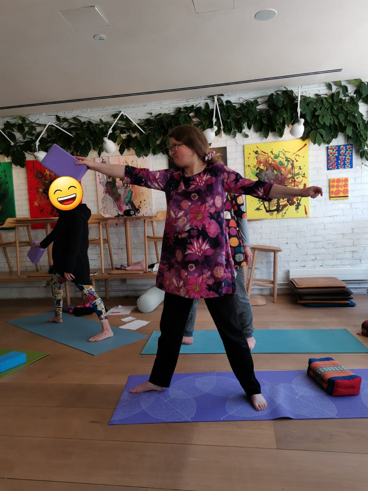 Girl wearing colorful dress doing warrior posture in yoga class