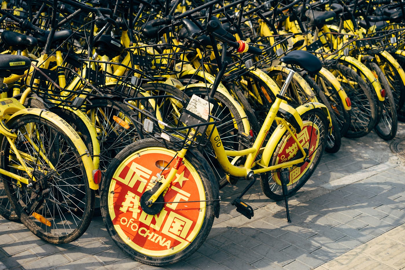 Many yellow bikes from the bike sharing program parked on streets