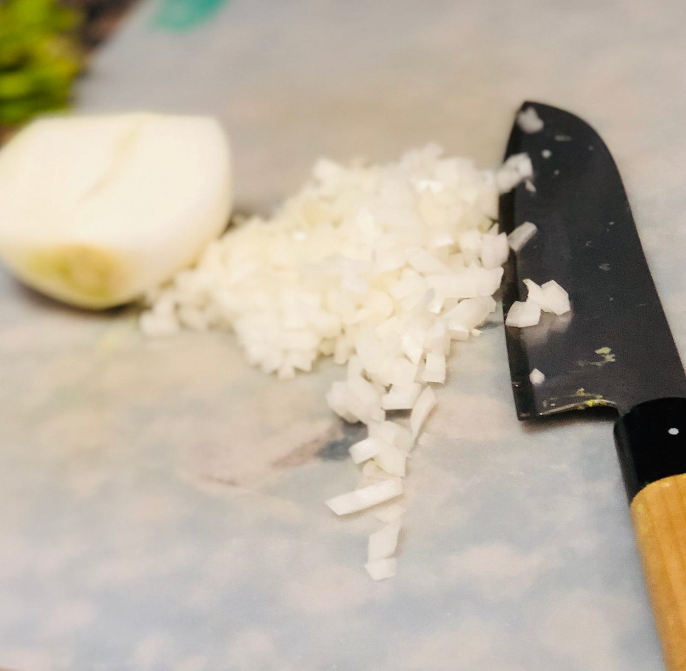 Onions chopped on a cutting board next to a sharp knife.