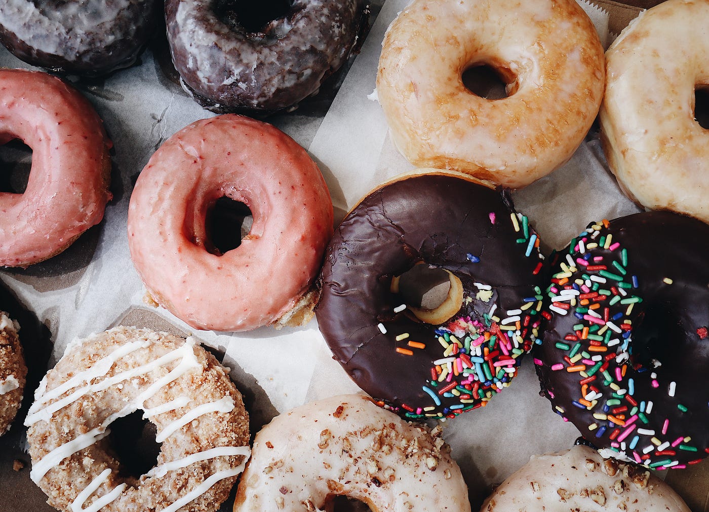 Donuts of different types: glazed chocolate cake, glazed, chocolate iced glaze with sprinkles, etc