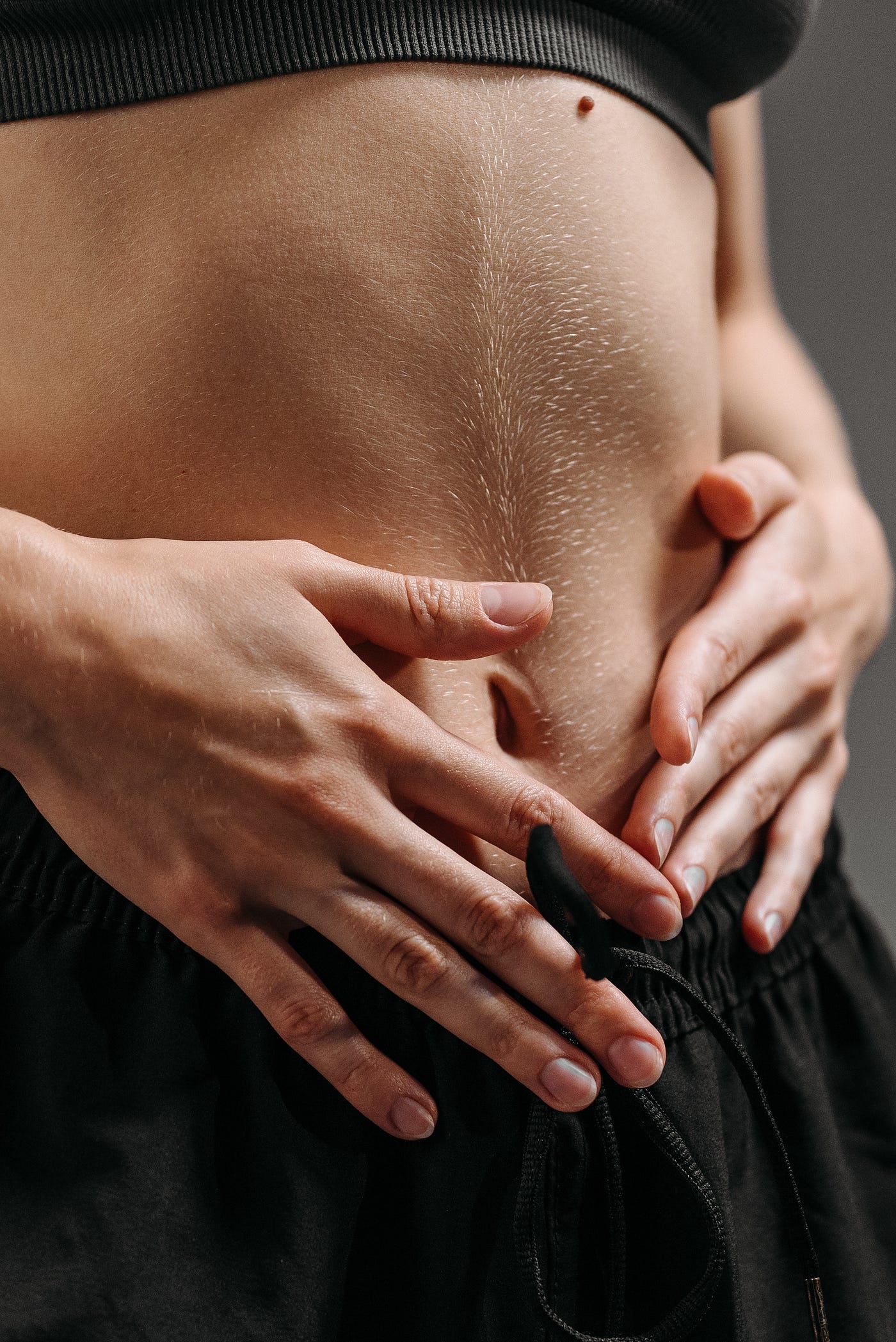 Person in Black Pants Holding Stomach