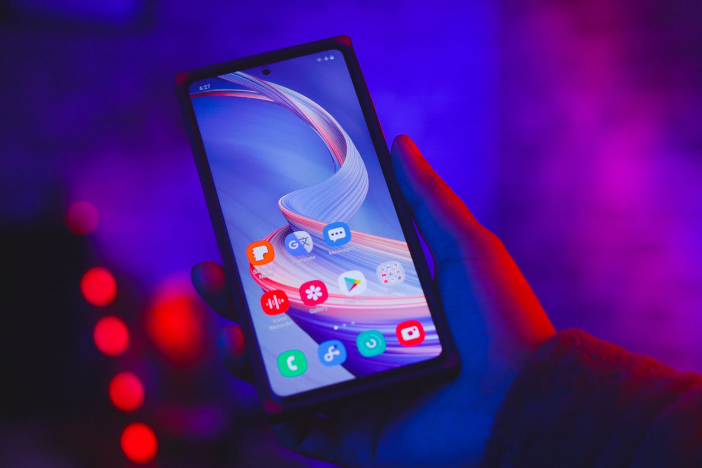 A smartphone in hand, in front of a blueish backgroud