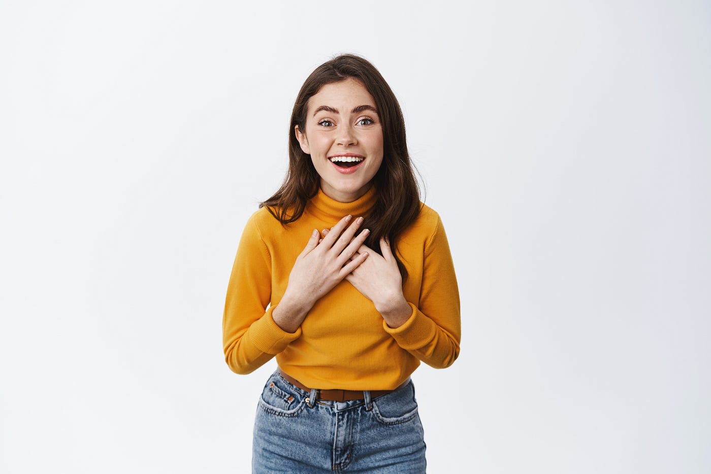 Young woman in gold turtleneck looking surprised, pleased, and touched.
