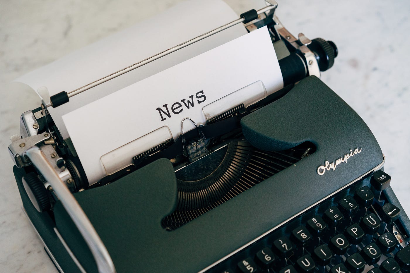 Typewriter with a document in the feeder stating “News”