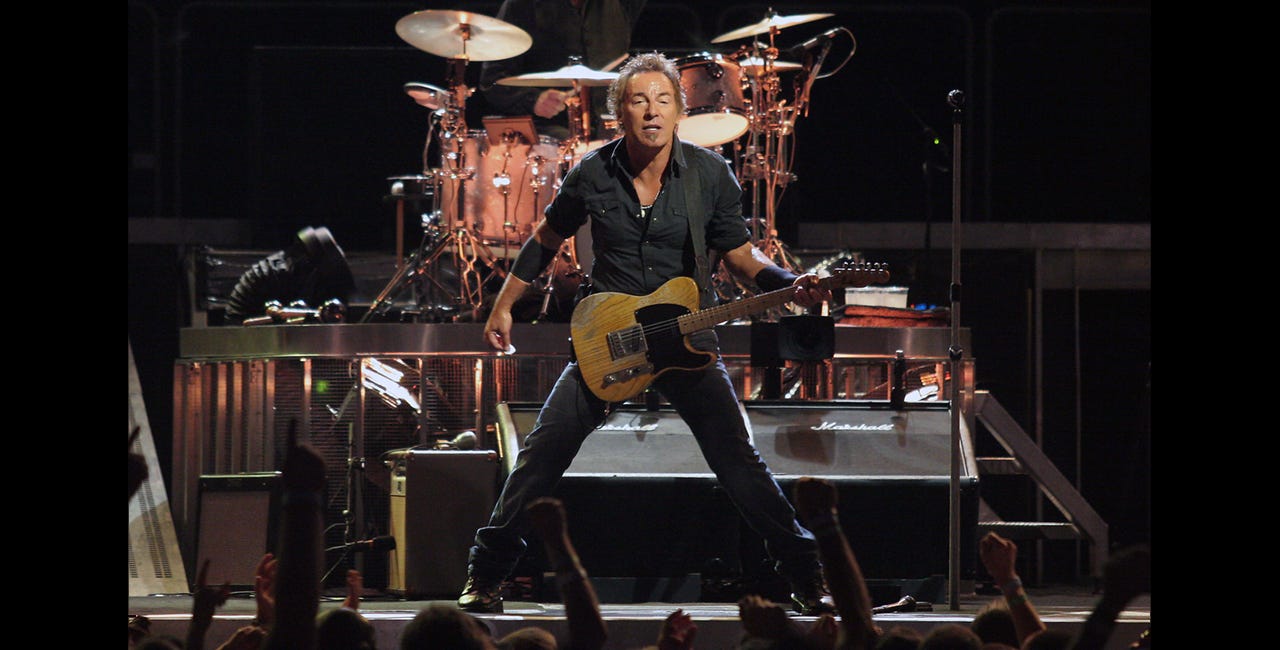 Bruce Springsteen on stage facing the audience, holding a Telecaster, and sweating heavily