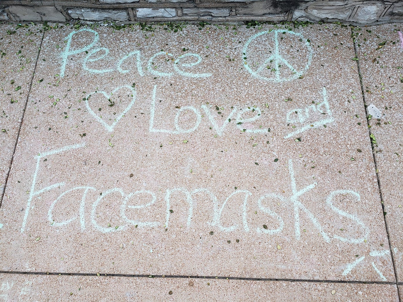 Sidewalk chalked in light blue “Peace, Love, and Facemasks” outside an elementary school.