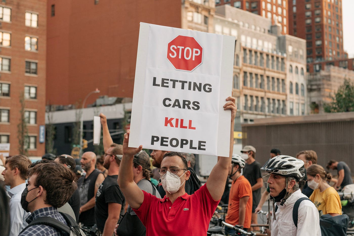 At a rally, a man holds up a sign that reads “STOP letting cars kill people”.