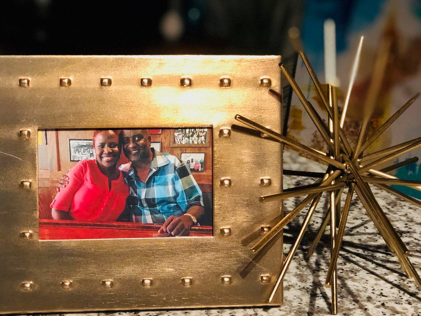 A decorative object next to a gold photo frame with a photo of a Black man and his daughter.