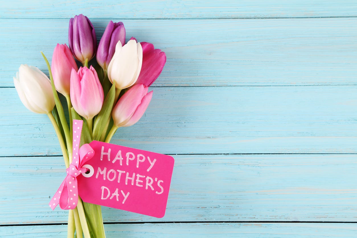 A bouquet of pink, purple and white tulips tied with a card that says Happy Mother’s Day.