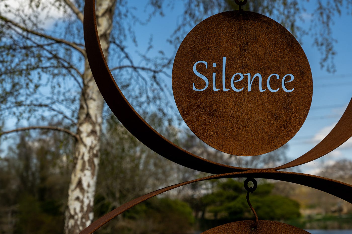A round metal sign with the word Silence, A Grain of Infinity, Medium