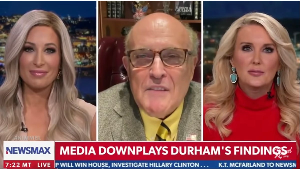 Old White Guy Rudy Giuliani, speaking on conservative news channel Newsmax, shown in a thumbnail between to much younger White women with long blond hair.