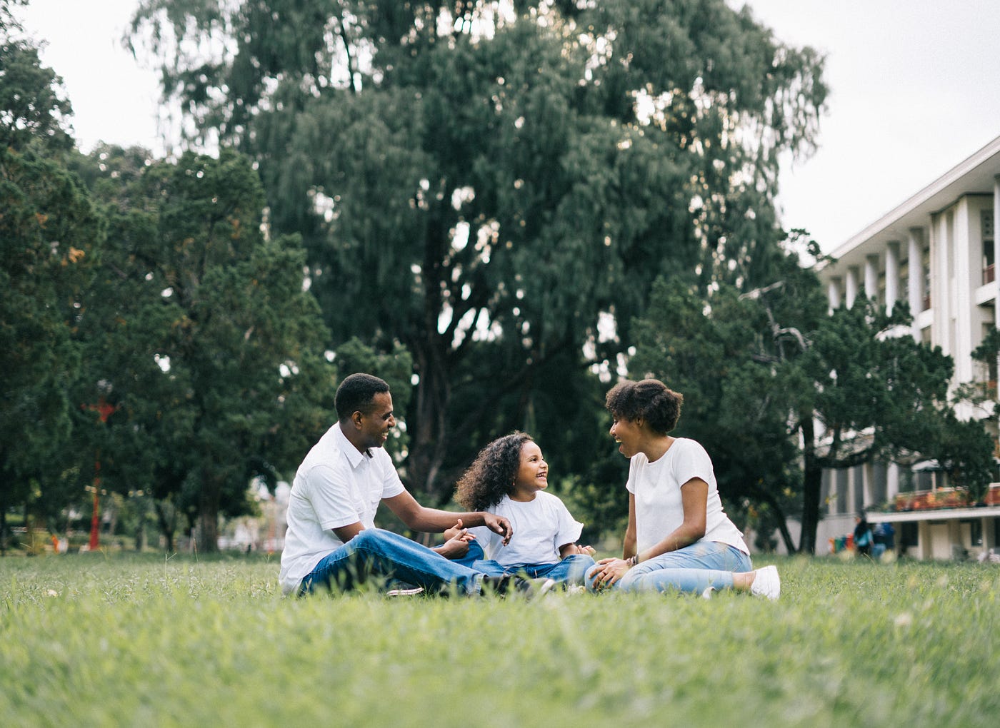 A family sitting in the grass wearing white shirts and blue jeans