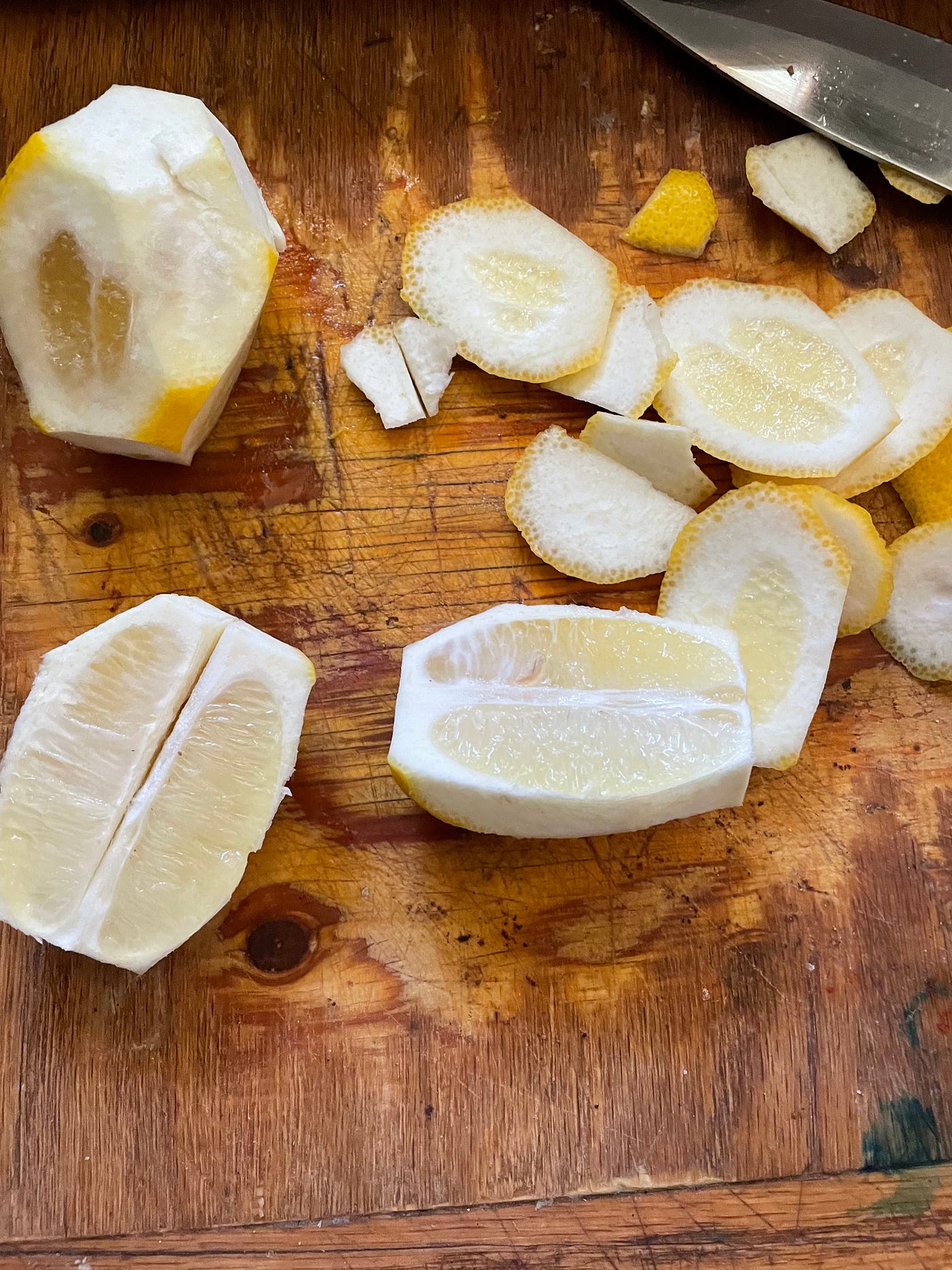 Lemons cut in half with the peel cut off on a cutting bored.