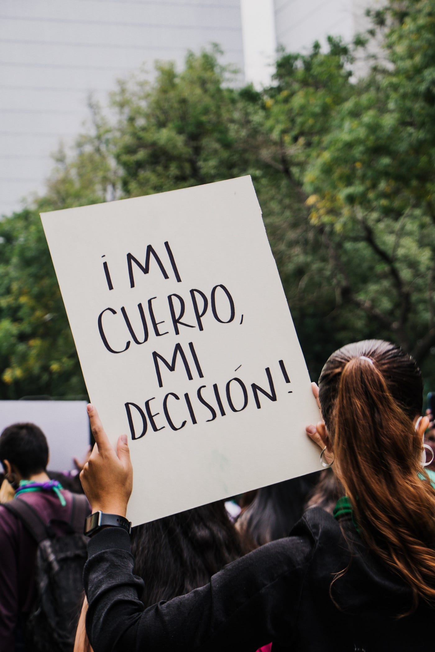 Photo of a person holding a sing that reads “My body, my choice” in Spanish.