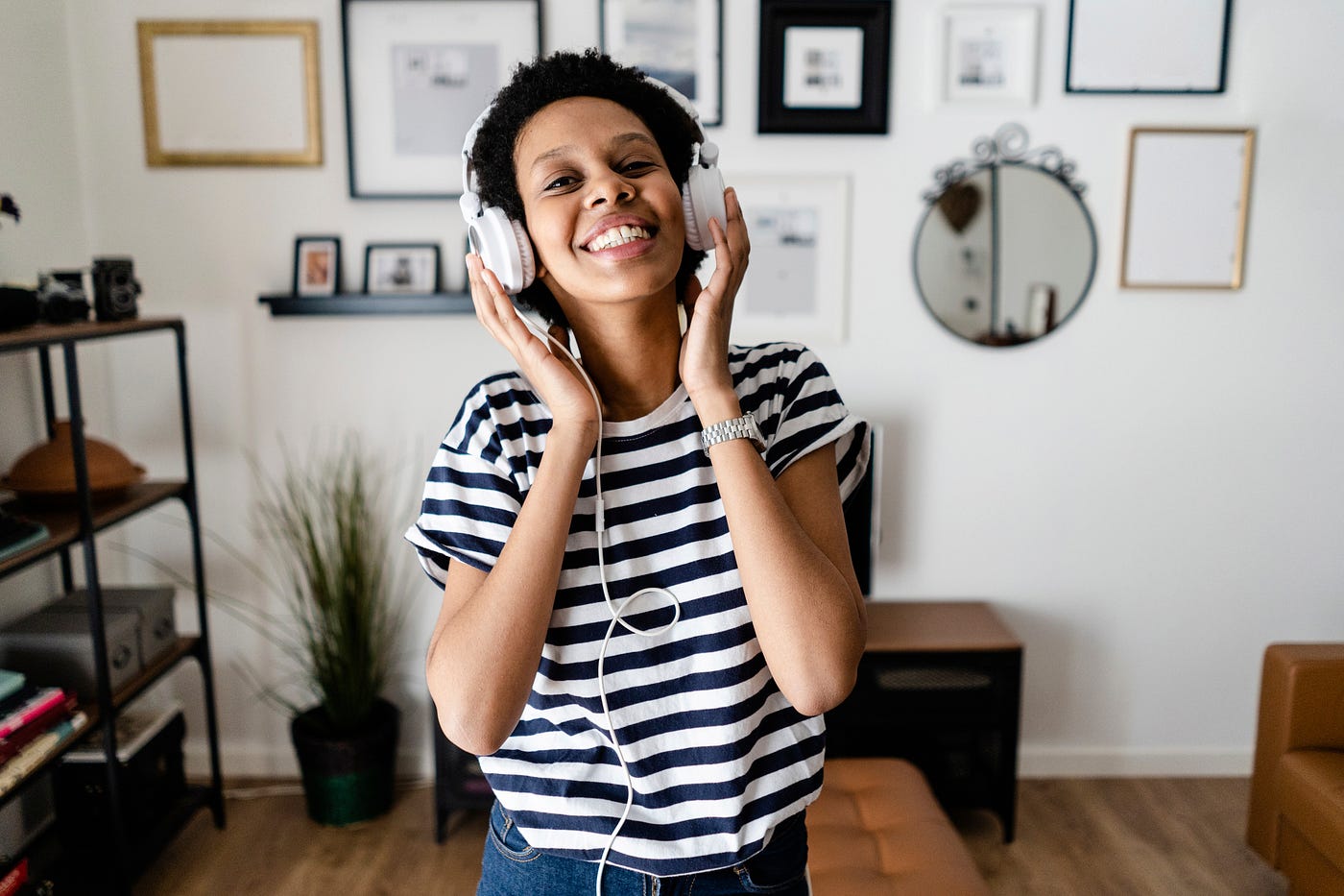 Black woman listening to music on headphones at home.