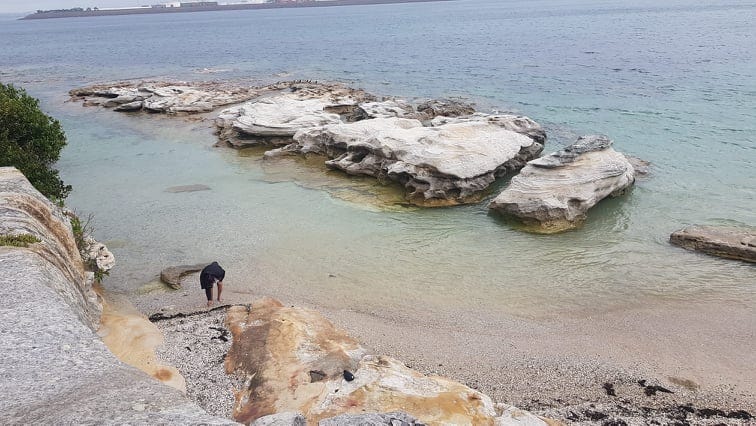 La Peruse Beach, Sydney Australia. There is seafoam green water surrounding white rocks. It is the edge of the cliff.