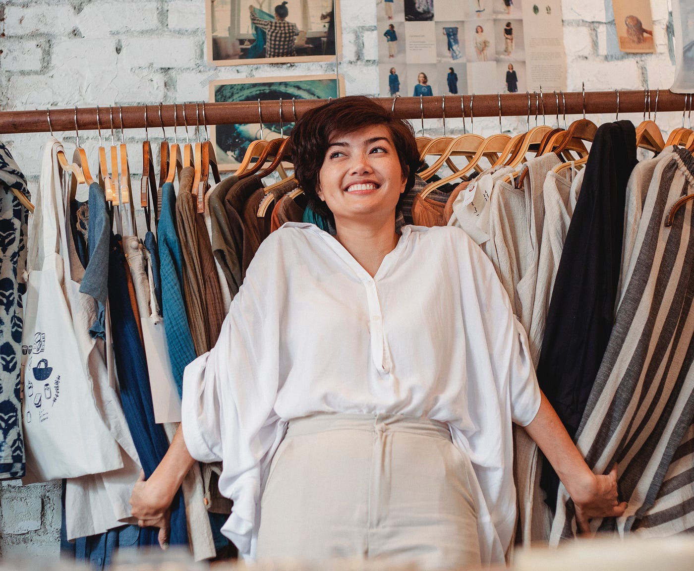 Woman smiling in front of a rack of clothes.