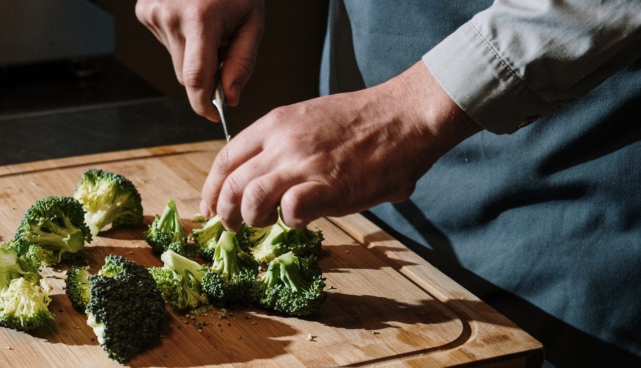 A close-up of a man chopping broccoli