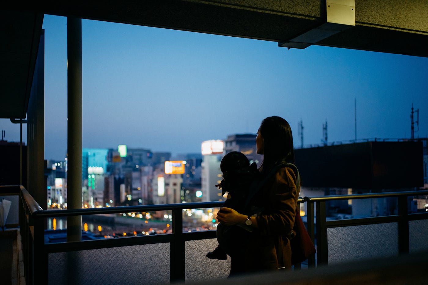 Mother with child looking out window at twilight.