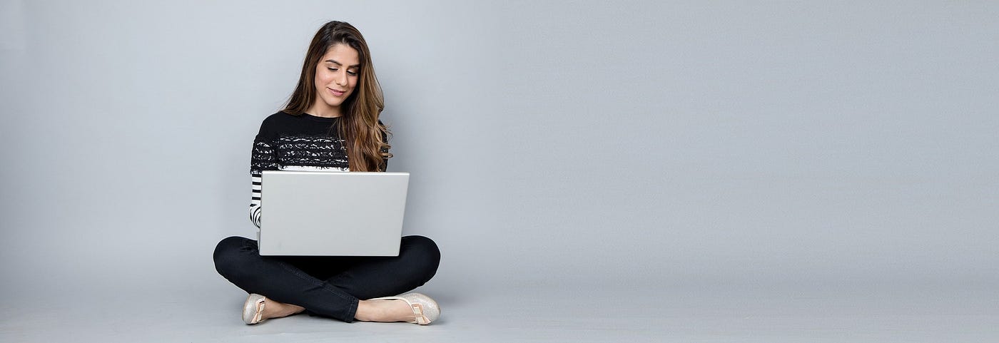 Woman sitting on the floor writing on a laptop