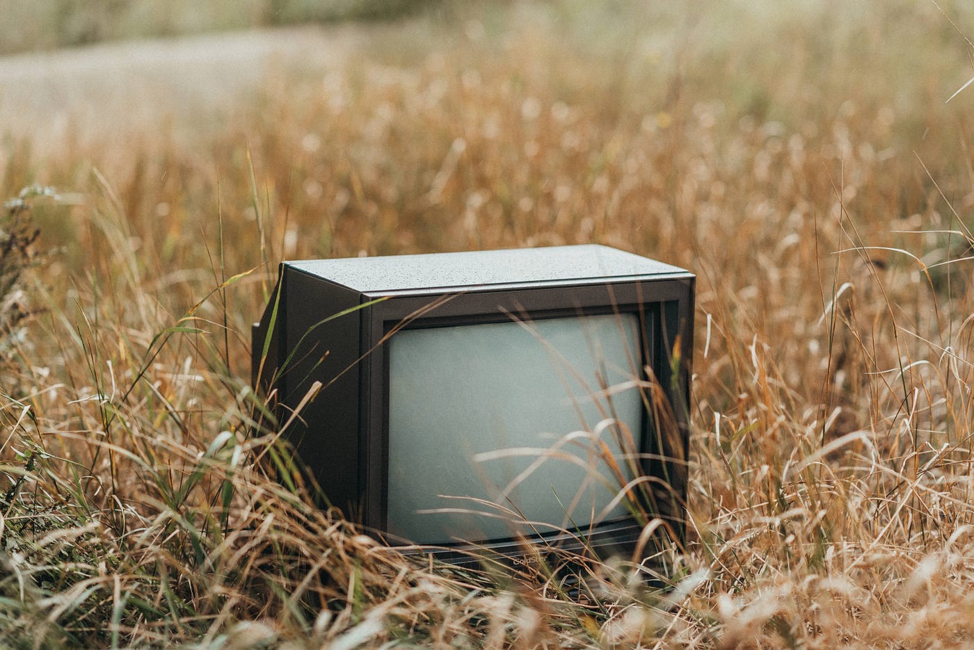 An old television sitting in a field.