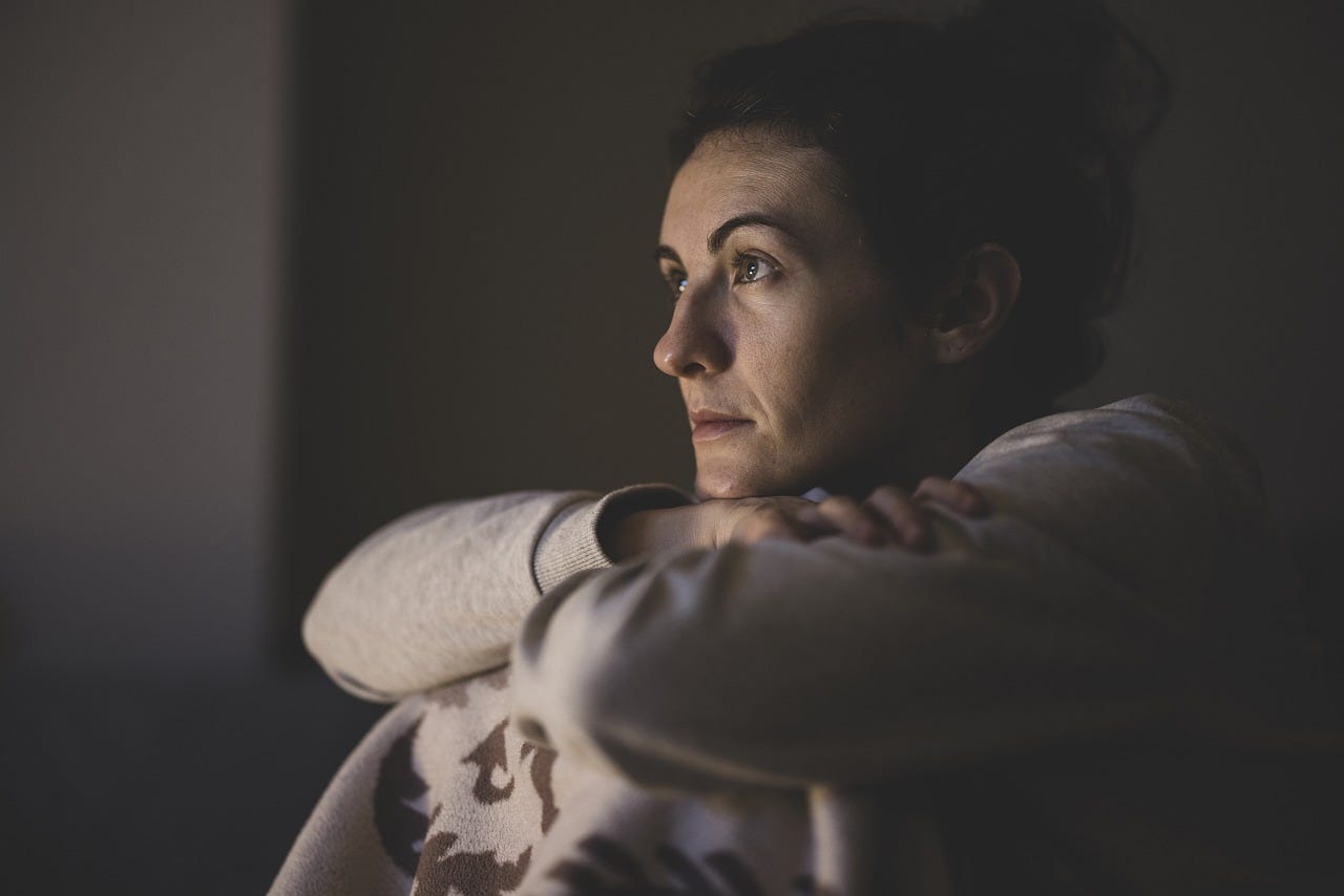A woman staring blankly, her face lit up by a TV screen.