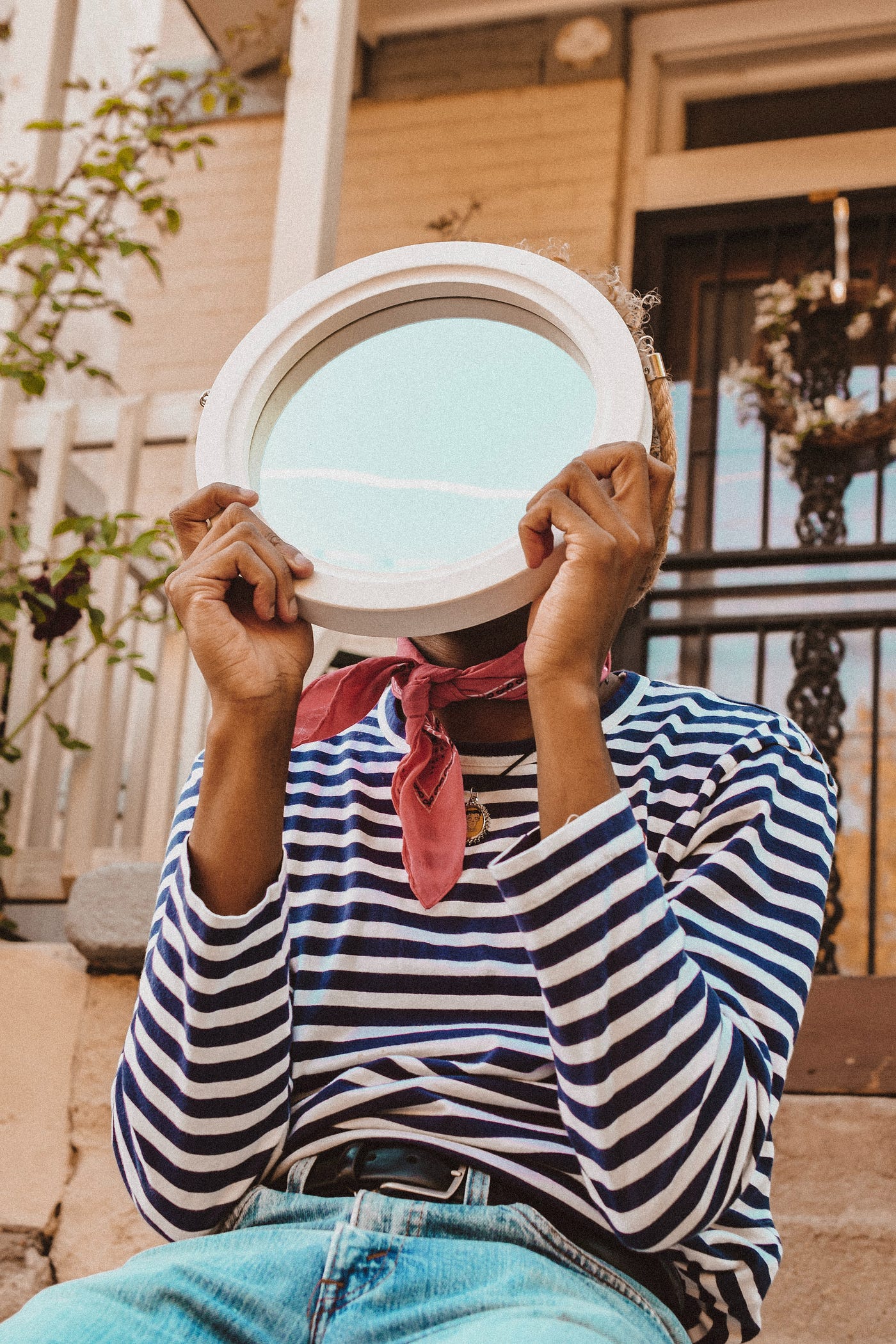 Black person holding a mirror over their face