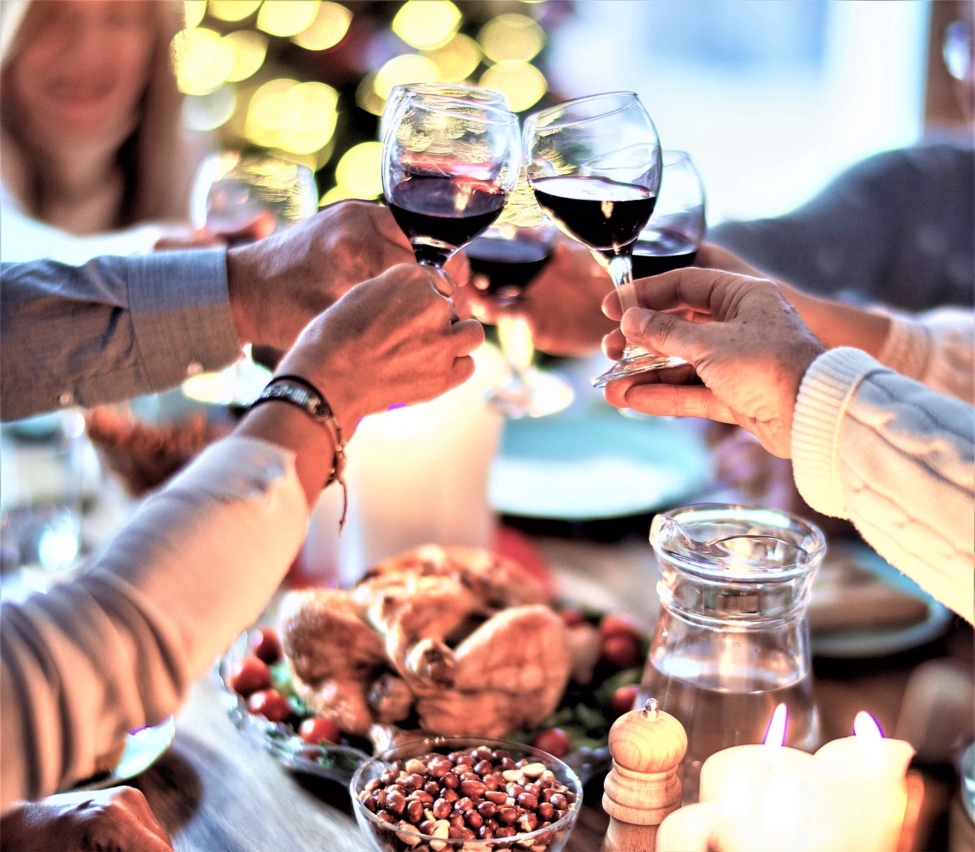 picture of holiday table filled with food, four people toasting wine glasses in center