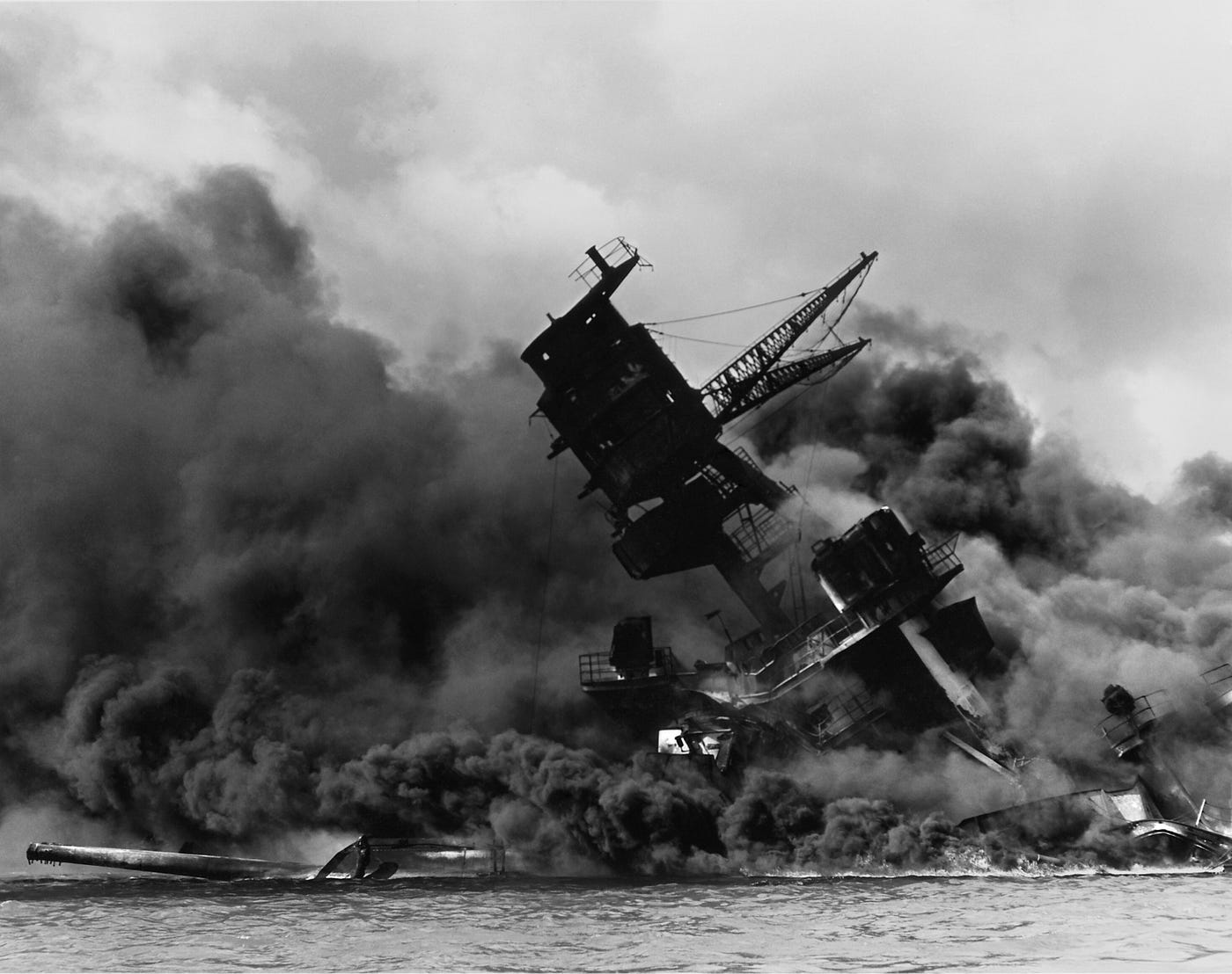 Black and white photo of warship sinking with surrounded by black smoke.