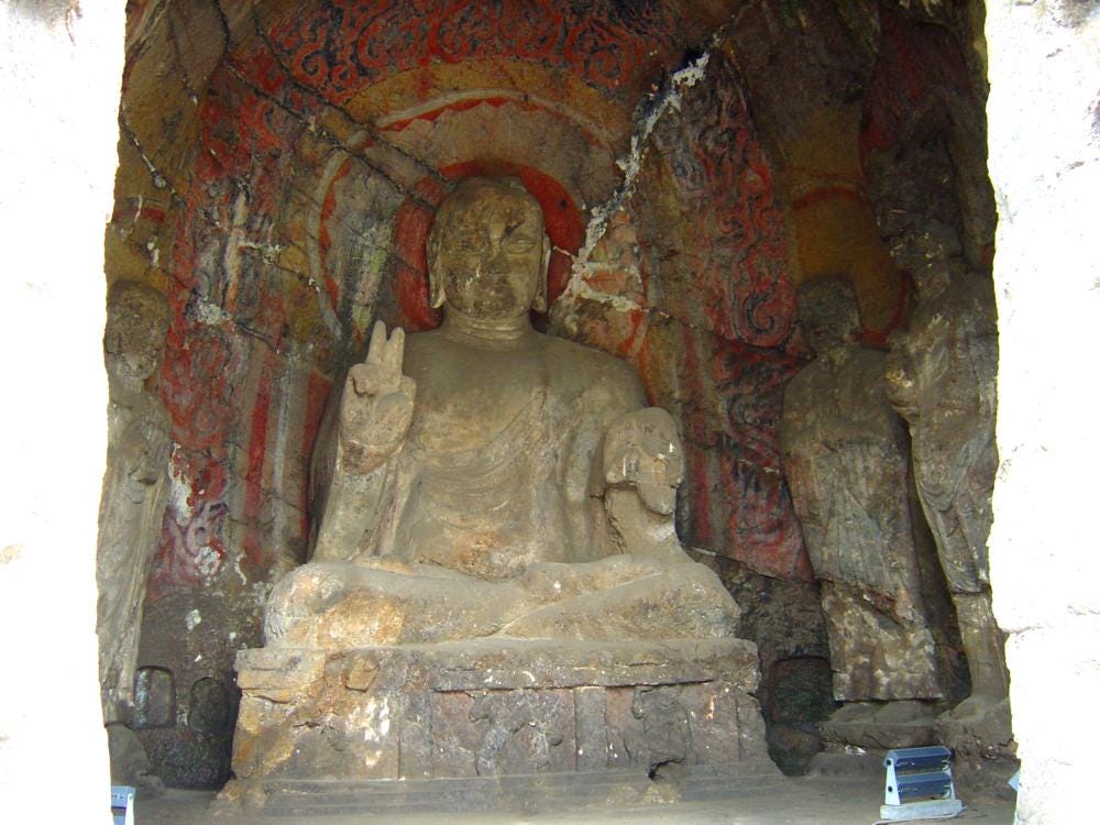 Stone Buddhist statue two fingers on right hand upraised in sacred gesture