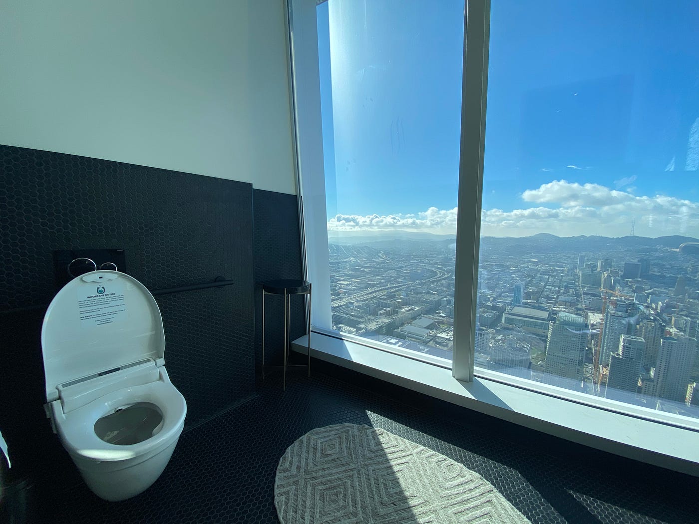 A photo of a smart toilet in a bathroom within a high-rise building overlooking the city.