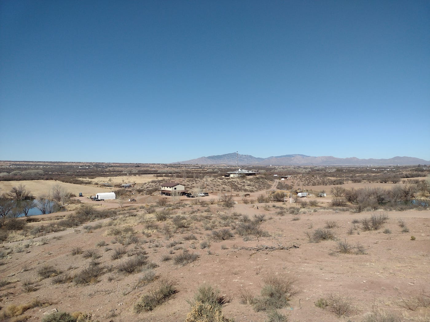 Landscape of rural Arizona desert with a ranch and a pond.