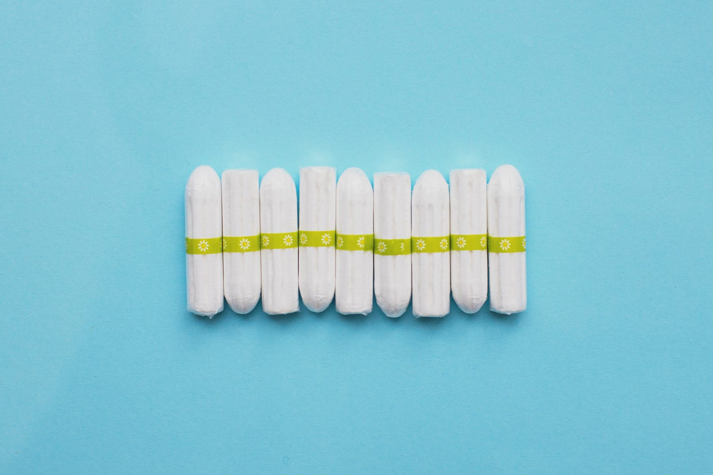 Nine tampons are lined up next to each other horizontally on a plain blue background.