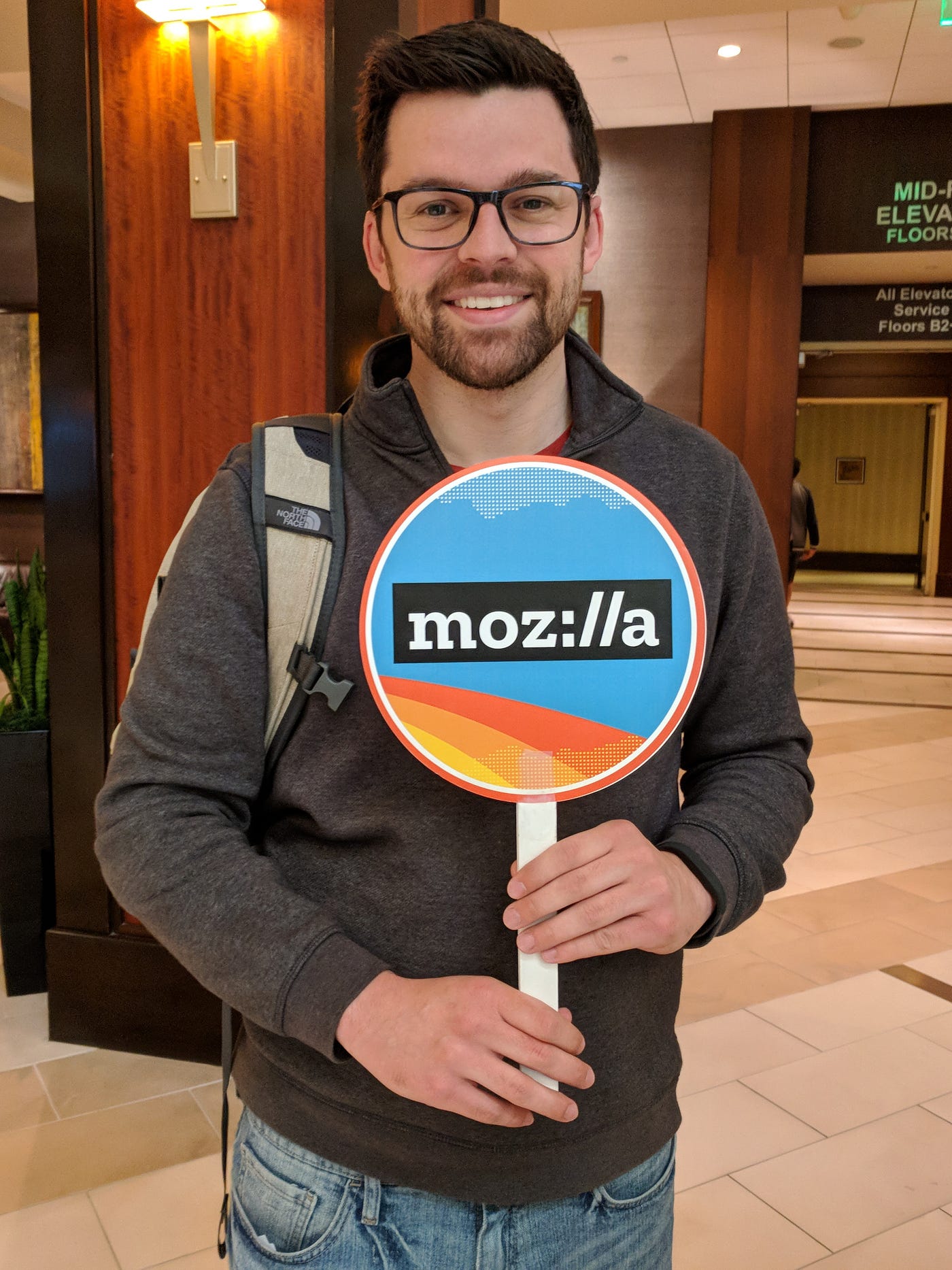 John Karahalis holding a sign with the Mozilla logo on it