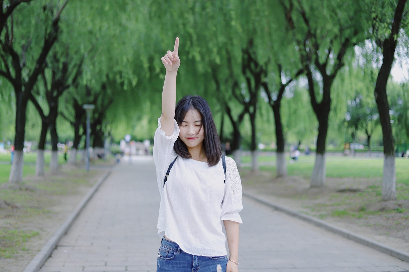 girl in a park pointing to the sky with index finger
