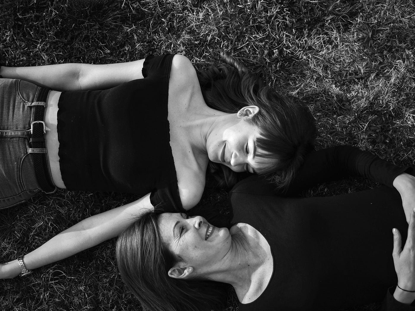 mother and teen daughter laying on grass