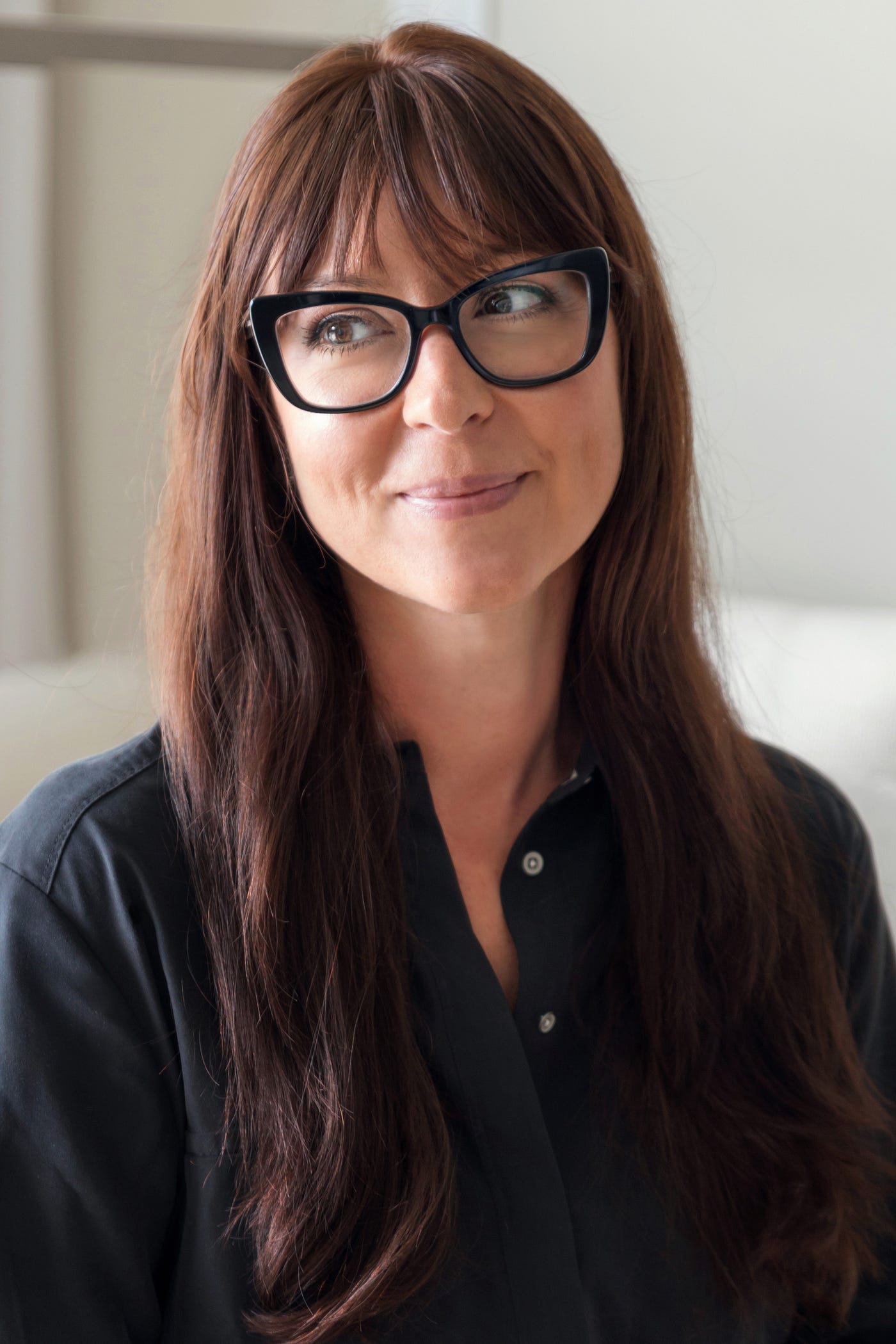 A portrait of LEED and WELL AP Interior designer, Sarah Barnard. Sarah is wearing a black blouse and black eye glasses.